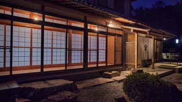 Un edificio japonés tradicional con grandes puertas correderas y un sendero de piedra que conduce a la entrada.