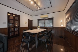 A conference room with a wooden table, chairs, a vase with flowers, a phone, and a wall-mounted air conditioner.