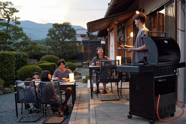 An outdoor dining area with a grill station, tables, and chairs.