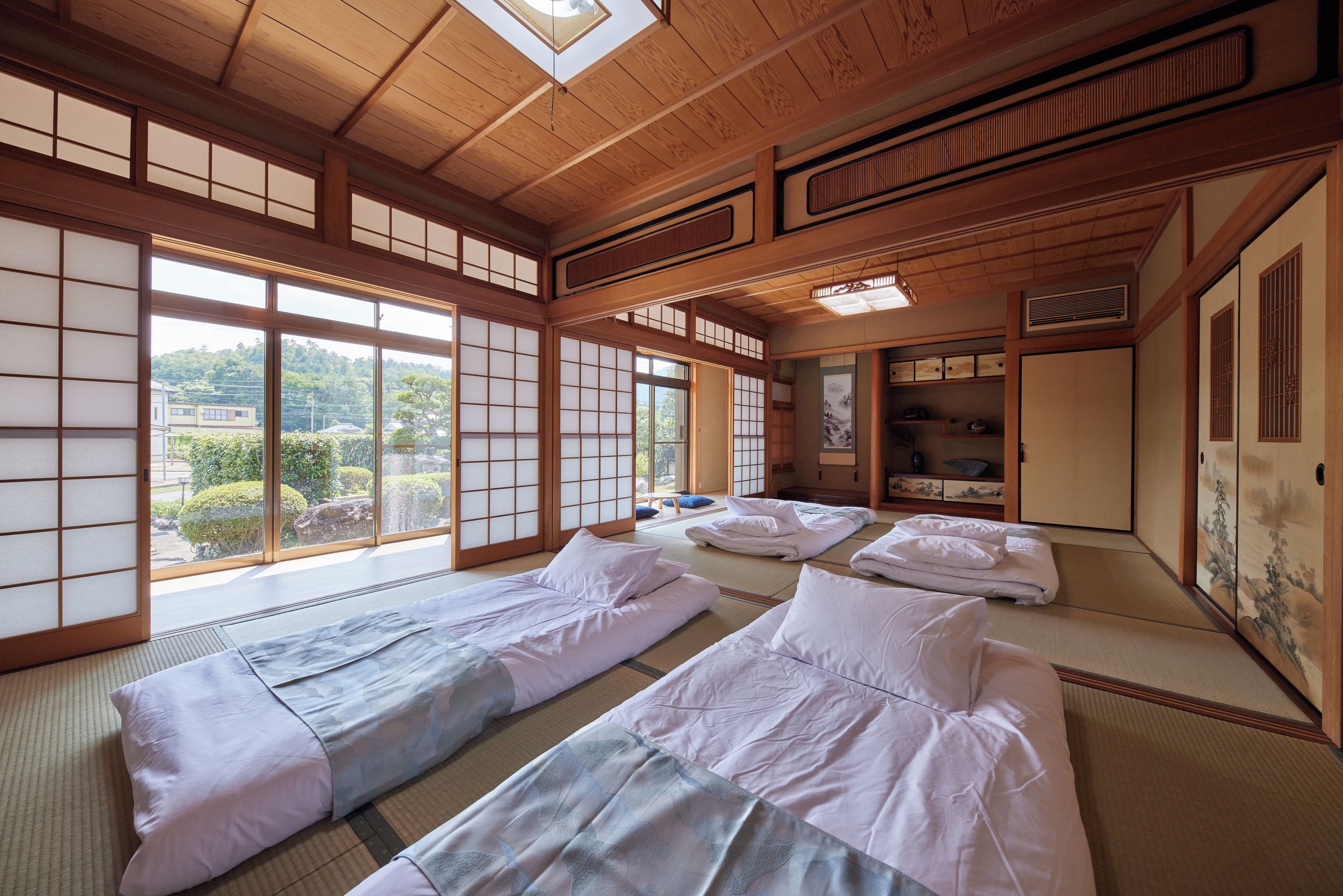 A traditional Japanese room with tatami flooring, shoji screens, and a futon bed setup.
