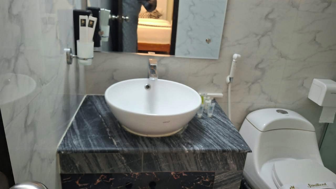 A bathroom with a marble sink, a toilet, and a mirror.