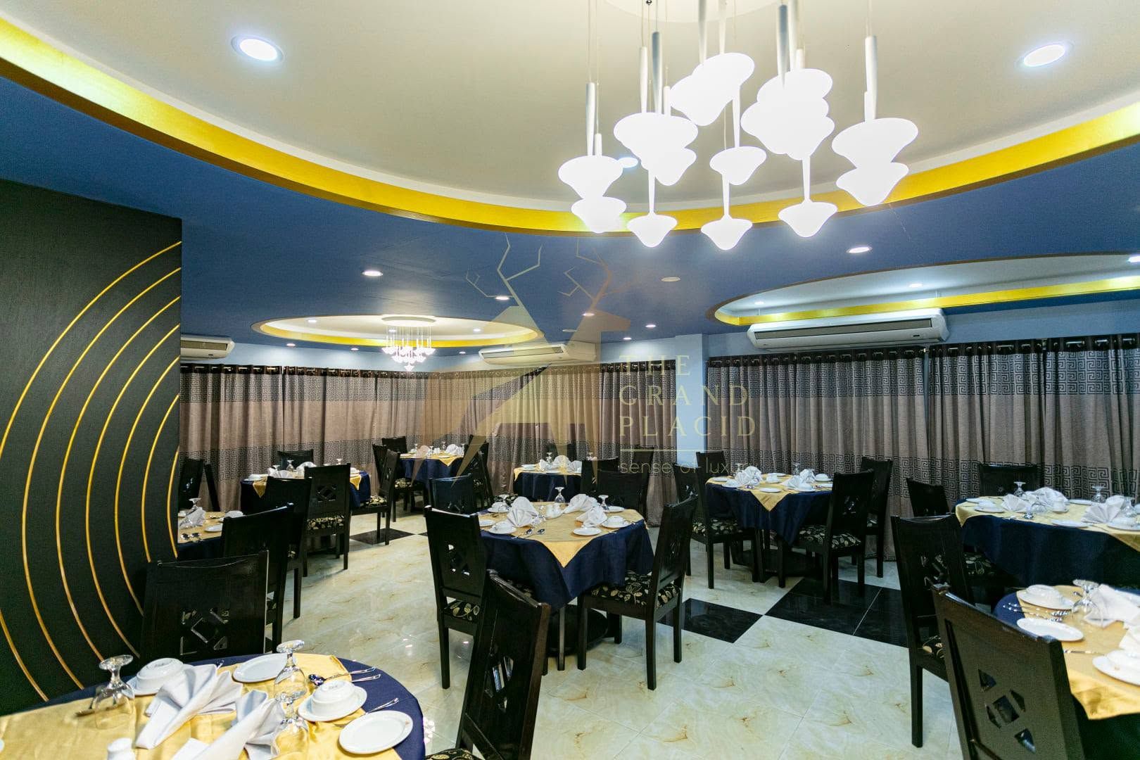 A restaurant with round tables, chairs, and a chandelier.