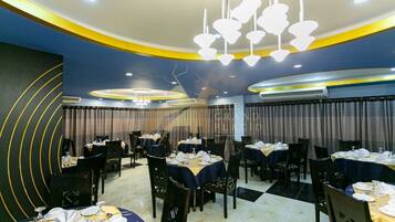 A restaurant with round tables, chairs, and a chandelier.