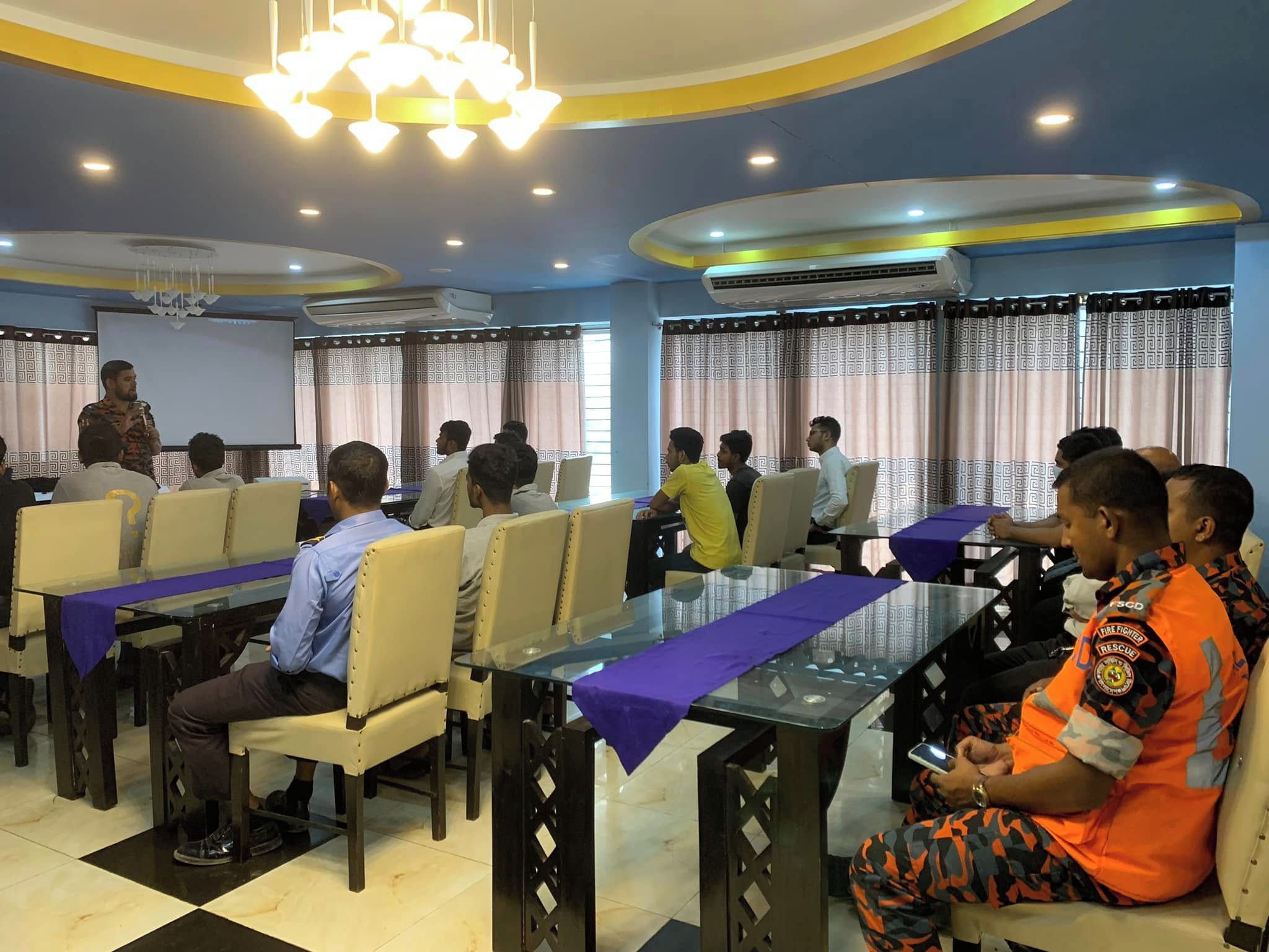 A conference room with a presentation area, multiple tables, and attendees seated.