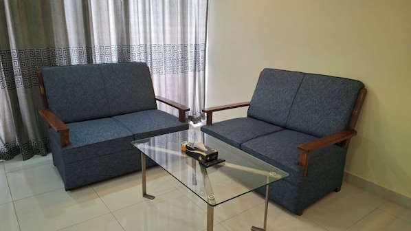 A room with two grey sofas and a glass coffee table. - The Grand Placid (Khulna)