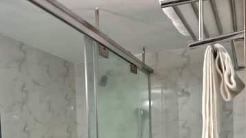 A bathroom with a glass shower enclosure, a toilet, and a towel rack.