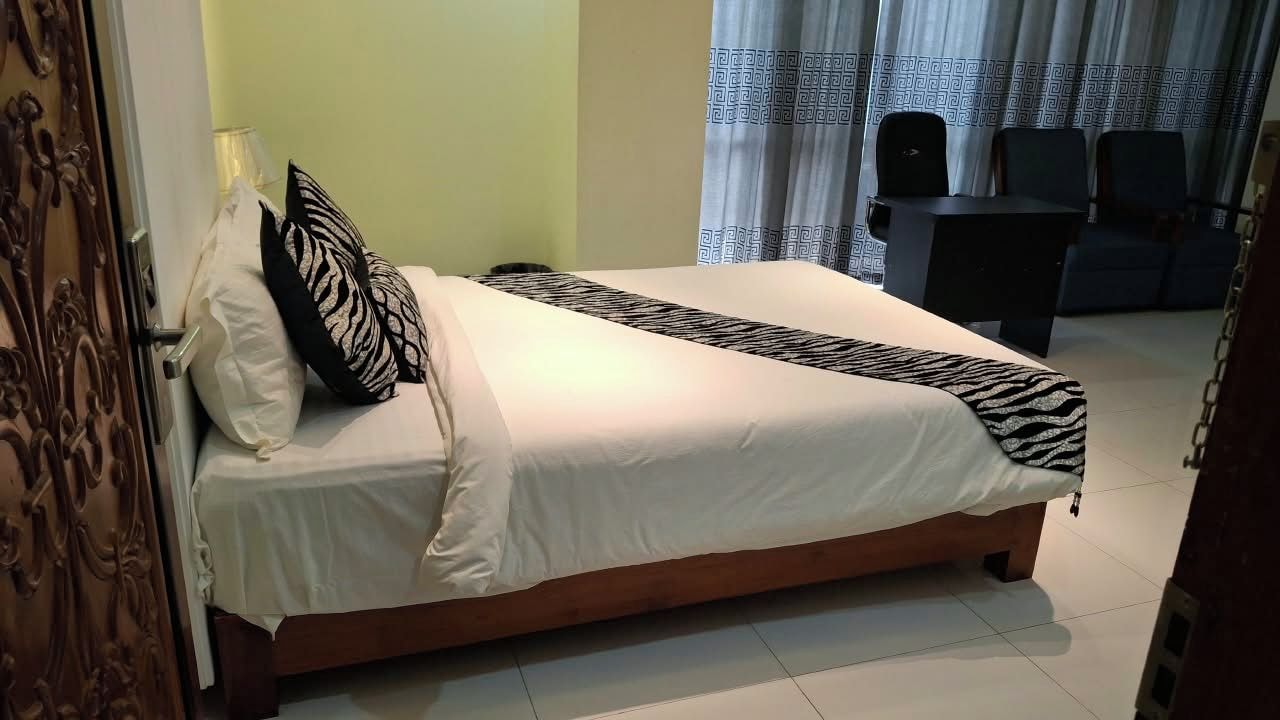 A hotel room with a bed, a desk, and a chair.