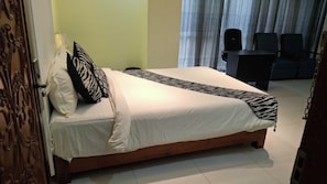 A hotel room with a bed, a desk, and a chair.