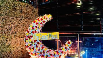 A decorative crescent made of flowers with a sign reading 'The Grand Place.'