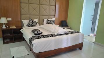 A hotel room with a bed, bedside table, lamp, and a view of the bathroom.