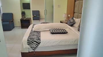 A hotel room with a bed, a chair, a small table, and a TV.