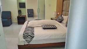 A hotel room with a bed, a chair, a small table, and a TV.