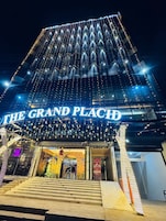 Un edificio con un letrero que dice 'THE GRAND PLACE' y una escalera que lleva a la entrada.