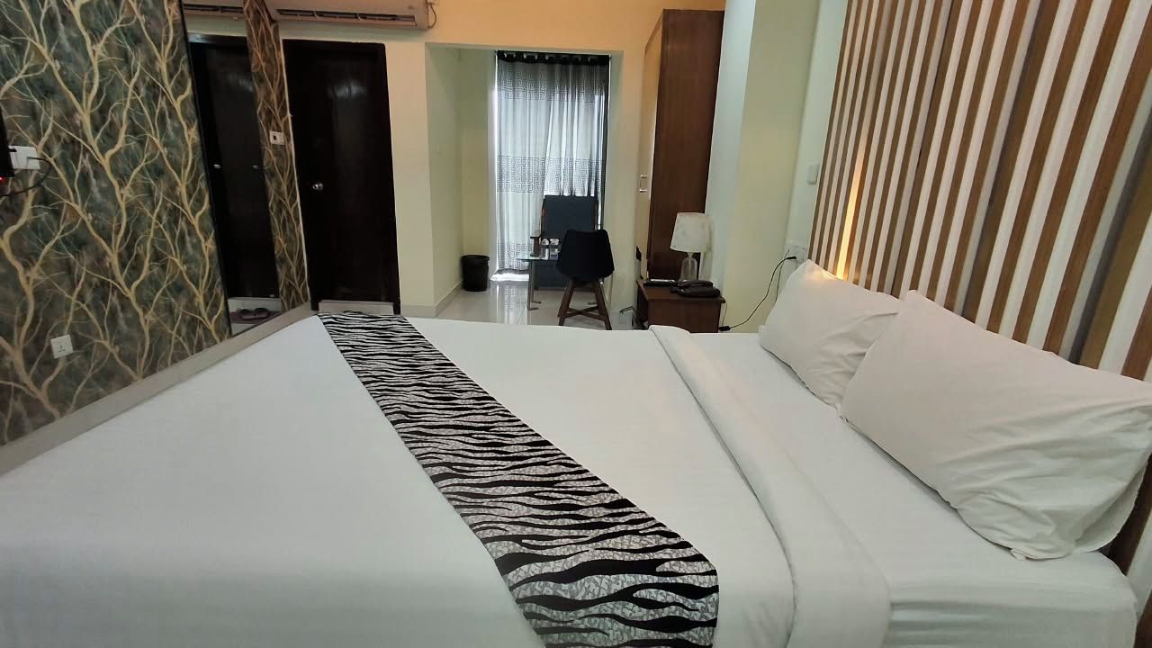 Ein Hotelzimmer mit Bett, Schreibtisch, Stuhl und einem fensterbepflanzten Fenster.