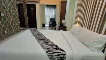 Ein Hotelzimmer mit Bett, Schreibtisch, Stuhl und einem fensterbepflanzten Fenster.