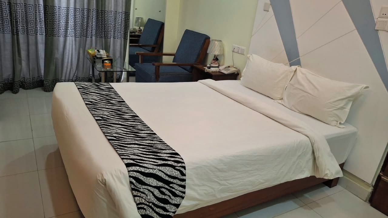 Une chambre d’hôtel avec un lit, une chaise, une petite table et une lampe.