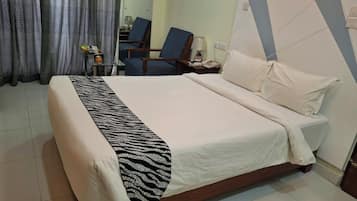 Une chambre d’hôtel avec un lit, une chaise, une petite table et une lampe.