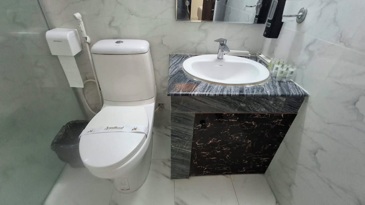 Een badkamer met toilet, wastafel en spiegel.