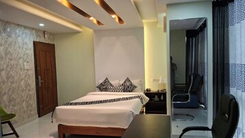 Habitación de hotel con cama, escritorio, silla y baño visible a través de una puerta abierta.