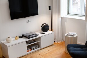 A modern living room with a flat-screen TV, a turntable, and a pair of headphones on a white console. - Sardina Living I (Porto)