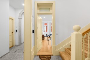 A hallway with a wooden floor, a welcome mat, and a staircase with a balustrade. - Sardina Living I (Porto)