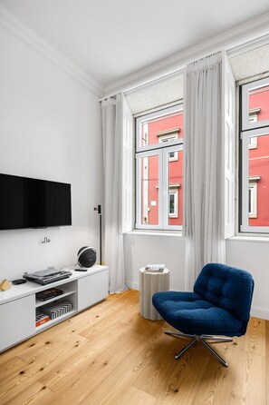 Un soggiorno moderno con una televisione a schermo piatto, una poltrona blu e un mobile TV bianco.