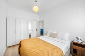 Une chambre à coucher comprenant un lit, une armoire, une table de chevet et un luminaire suspendu.