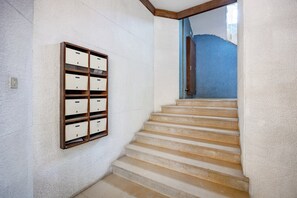 A staircase with a wooden handrail and a wall-mounted storage unit with multiple compartments. - Bright Apartment | Trindade & City Centre (Porto)