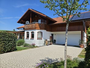 Ein zweigeschossiges Haus mit Balkon, Garage und befestigter Auffahrt.