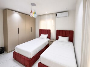 Ein Hotelzimmer mit zwei Betten, einem Kleiderschrank, einer Klimaanlage und einer Pendelleuchte.