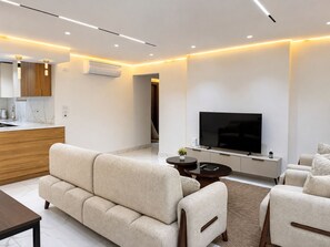 Ein modernes Wohnzimmer mit einer Couch, einem Fernseher und einem kleinen Couchtisch.
