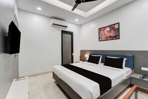 Una habitación de hotel moderna con cama, mesita de noche, lámpara y una obra de arte en la pared.