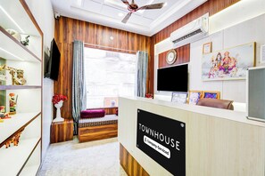 Un espace d’accueil avec un comptoir de réception en bois, une horloge et un téléviseur fixé au mur.