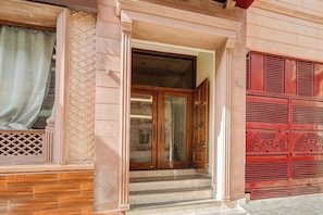 A building entrance with a wooden door and steps leading up to it.