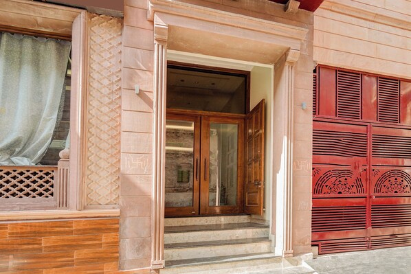 A building entrance with a wooden door and steps leading up to it.
