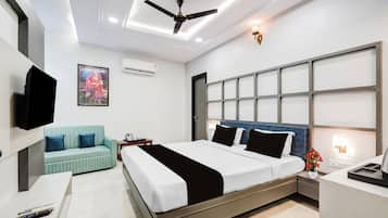 A modern bedroom with a bed, a sofa, a TV, and an air conditioning unit.