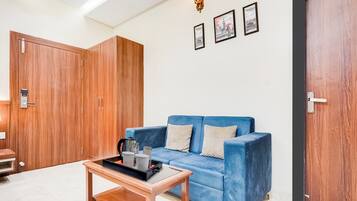 Ein Zimmer mit einem blauen Sofa, einem Holzschrank, einem Couchtisch und einer Tür.