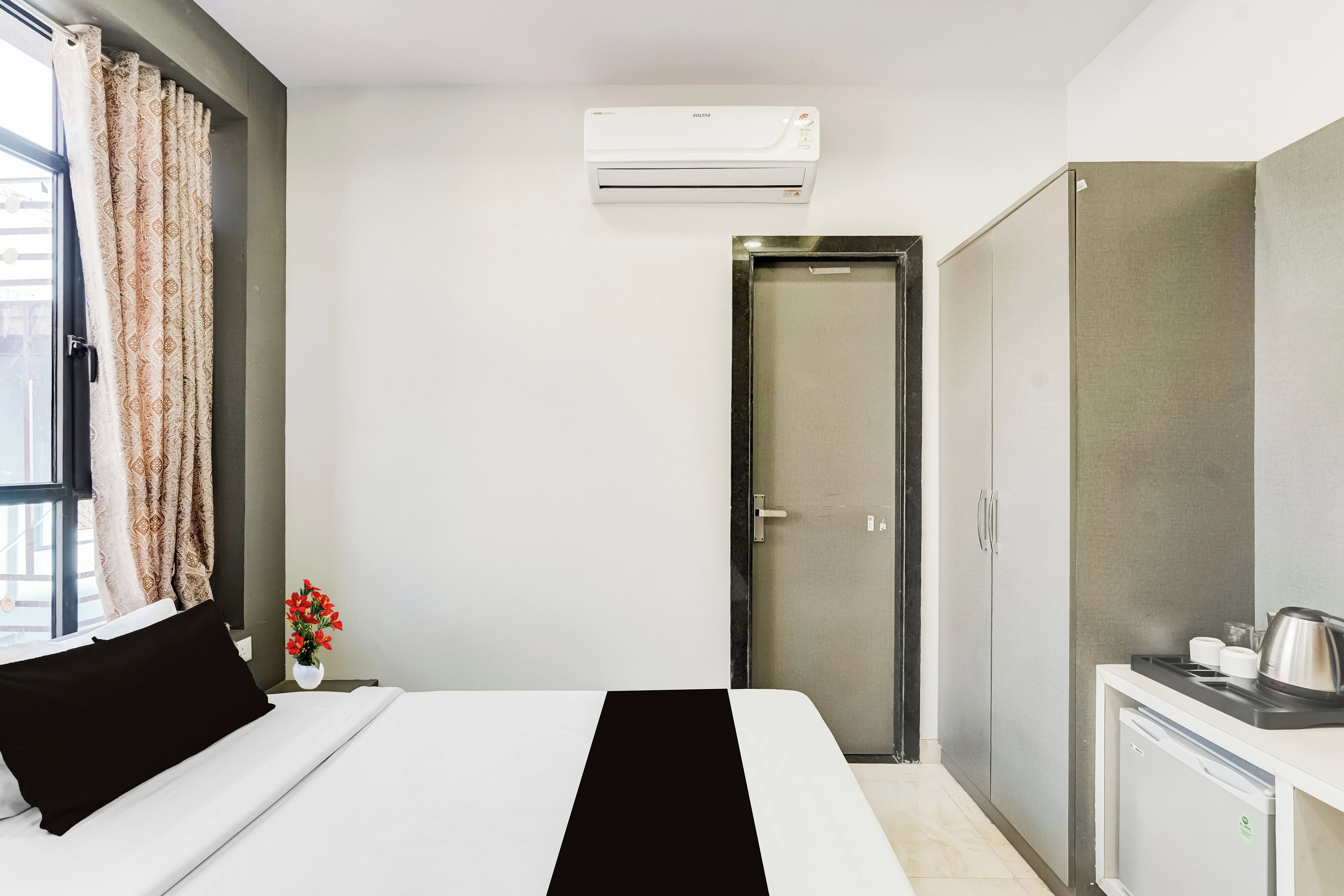 Una habitación de hotel con cama, armario, kitchenette pequeño y aire acondicionado.