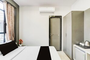Une chambre d’hôtel comprenant un lit, une armoire, une petite kitchenette et un appareil de climatisation.
