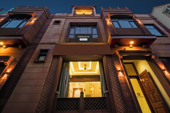 Una casa adosada con una entrada destacada, un letrero que indica que es una casa adosada y un frente bien iluminado.
