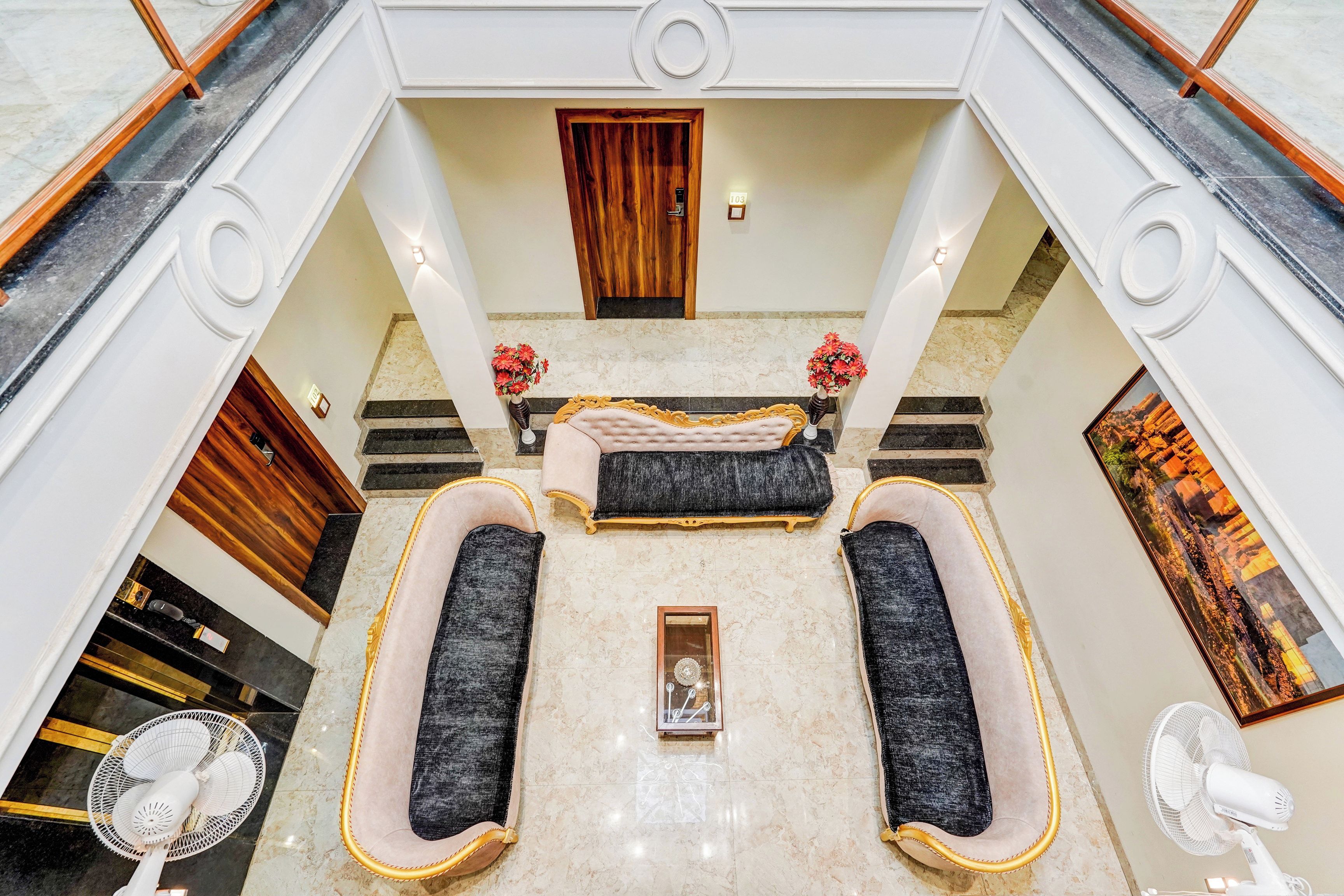 Eine Hotelhalle mit Marmorboden, einer Rezeption, einer Sofagarnitur und einem Gemälde an der Wand.