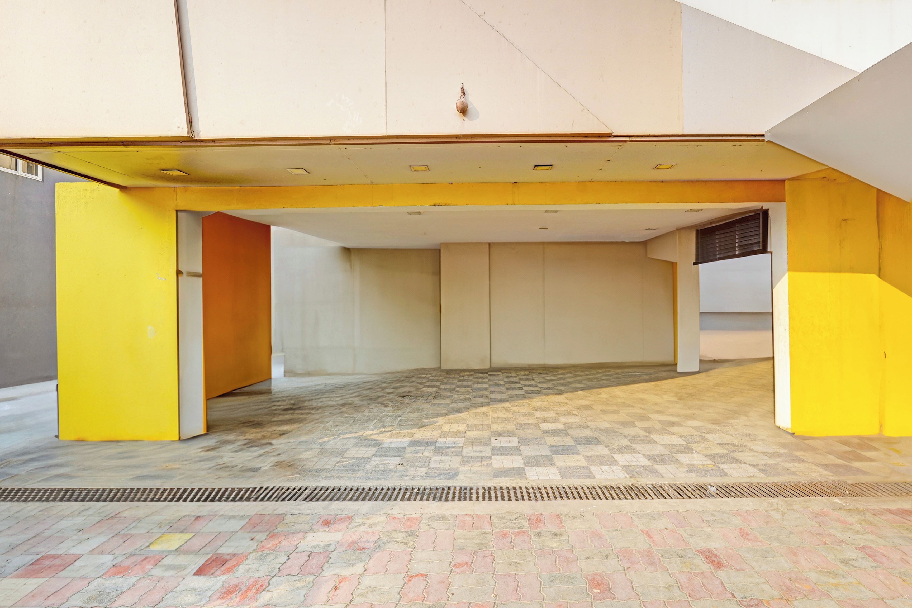Un espacio interior con piso a cuadros, paredes amarillas y techo inclinado.