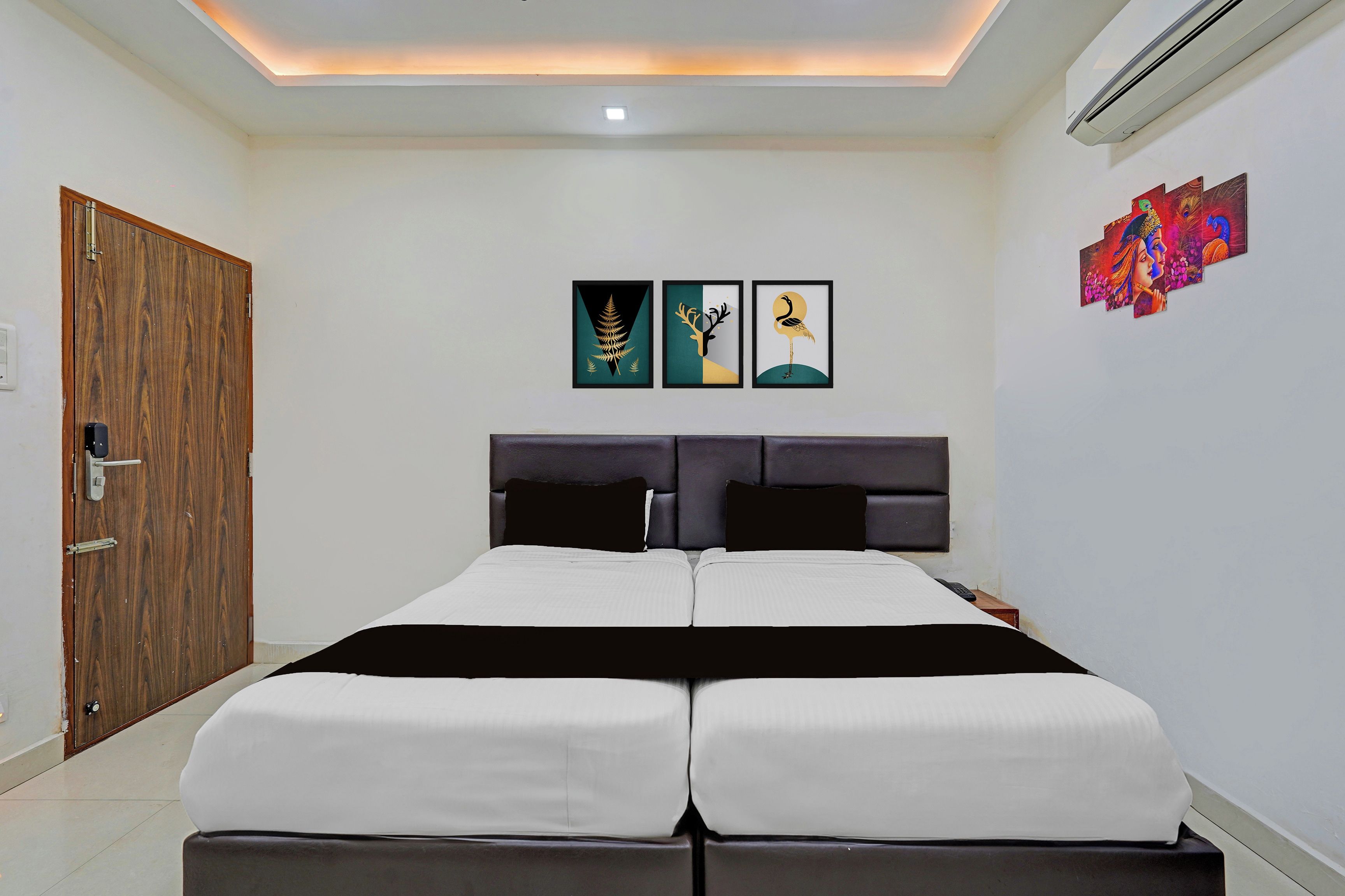 Un dormitorio con una cama doble, una puerta de madera y tres cuadros en la pared.