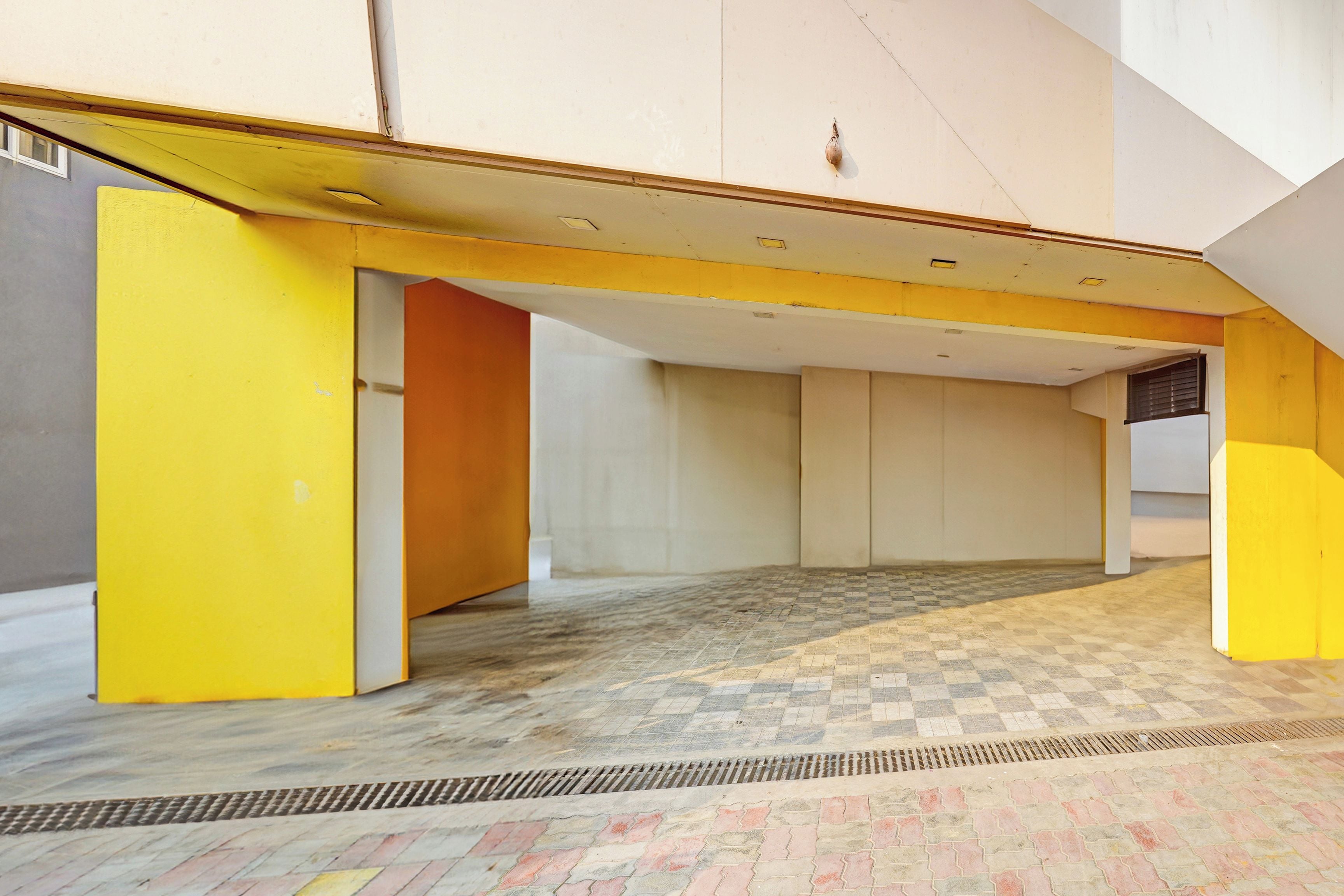 Un espacio interior con techo alto, piso a cuadros y pared amarilla.