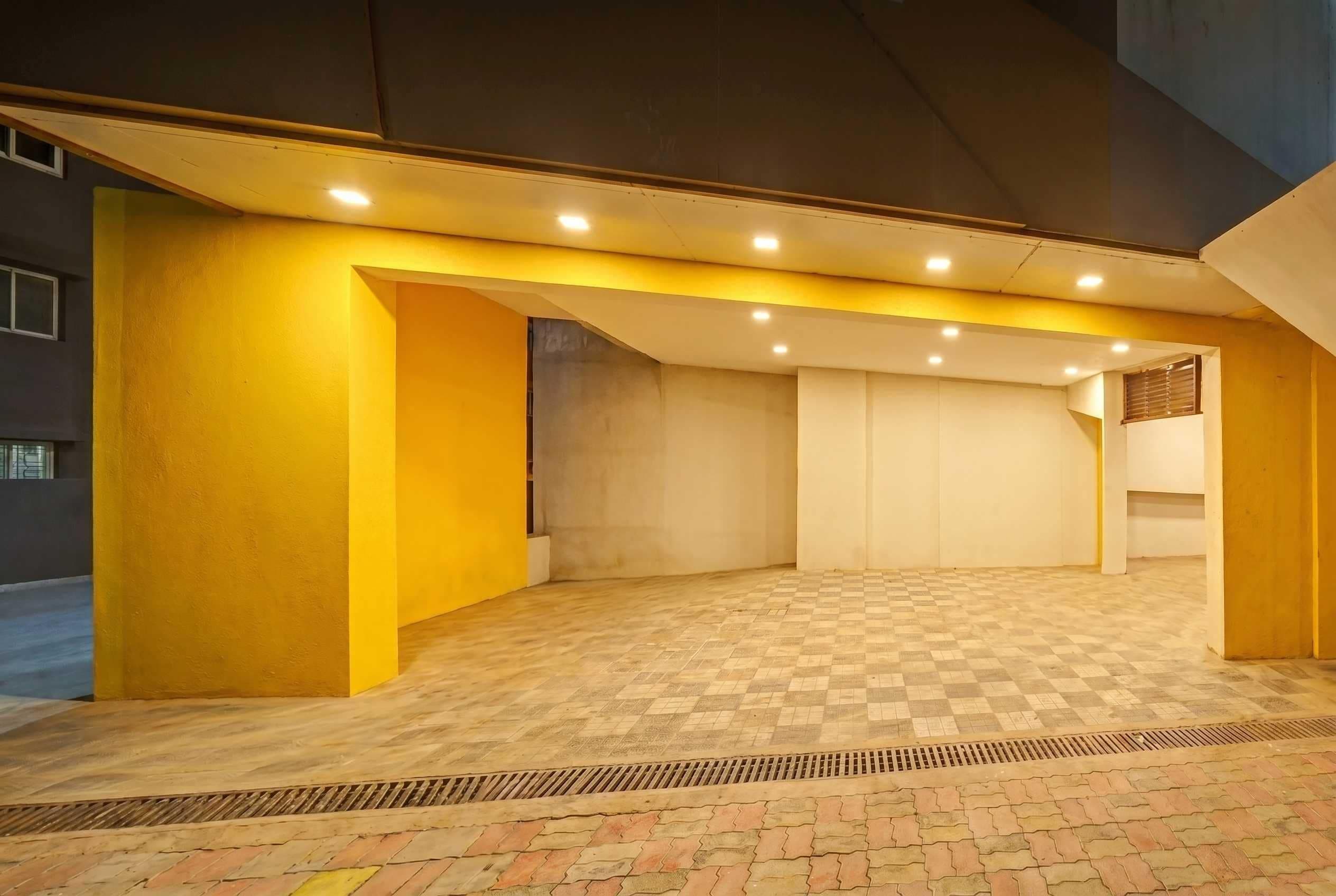 An indoor area with a checkered floor, yellow walls, and recessed lighting.