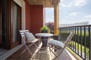 A balcony with two white folding chairs, a small round table, and a potted plant. - A bright 75-square-meter three-room apartment, for up to six guests, located on the first floor of a building (equipped with an elevator, though not suitable for people with disabilities).It enjoys a strategic location near Veronafiere and offers excelle (Verona)