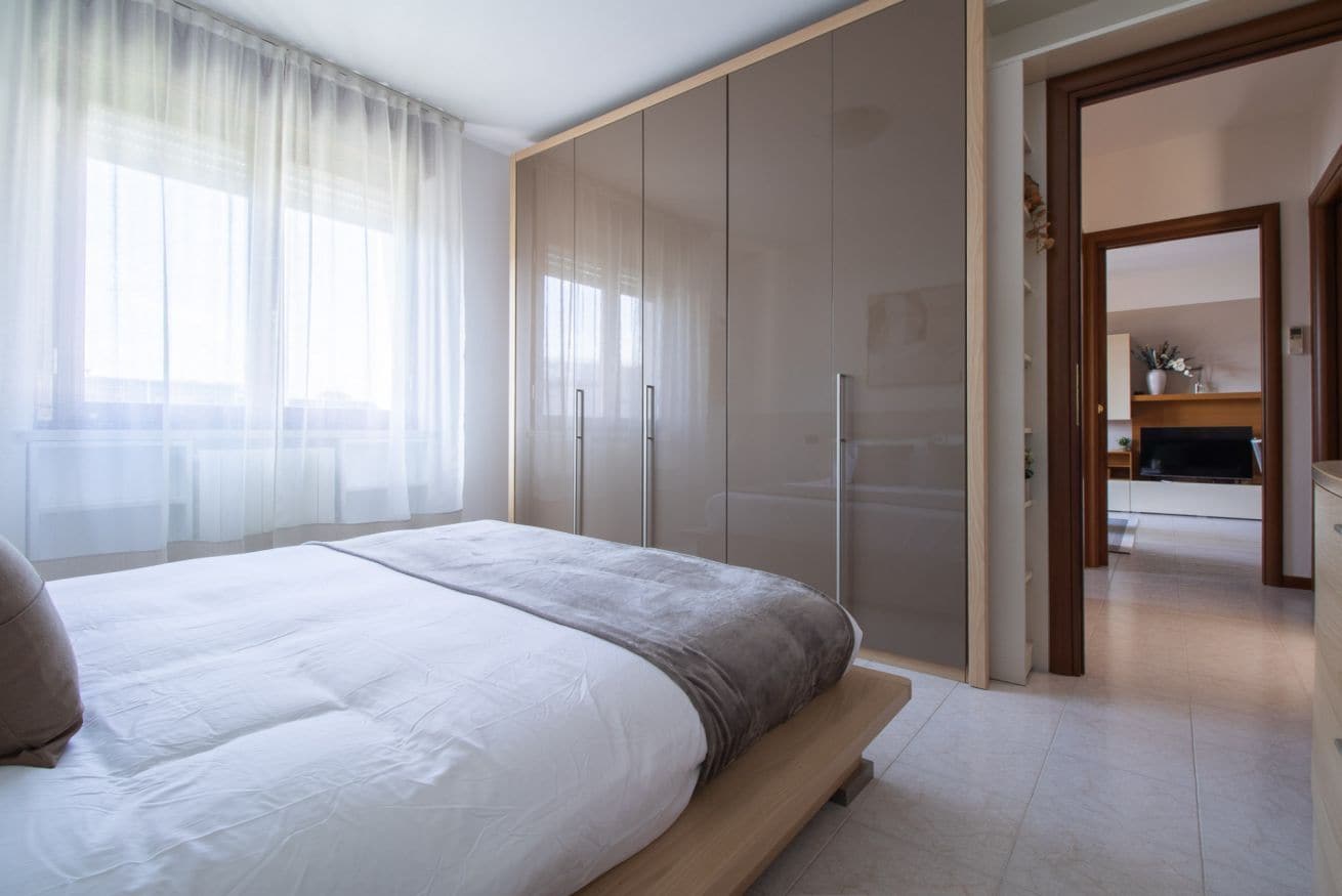 Una camera da letto con un letto, un armadio e vista su un'altra stanza.