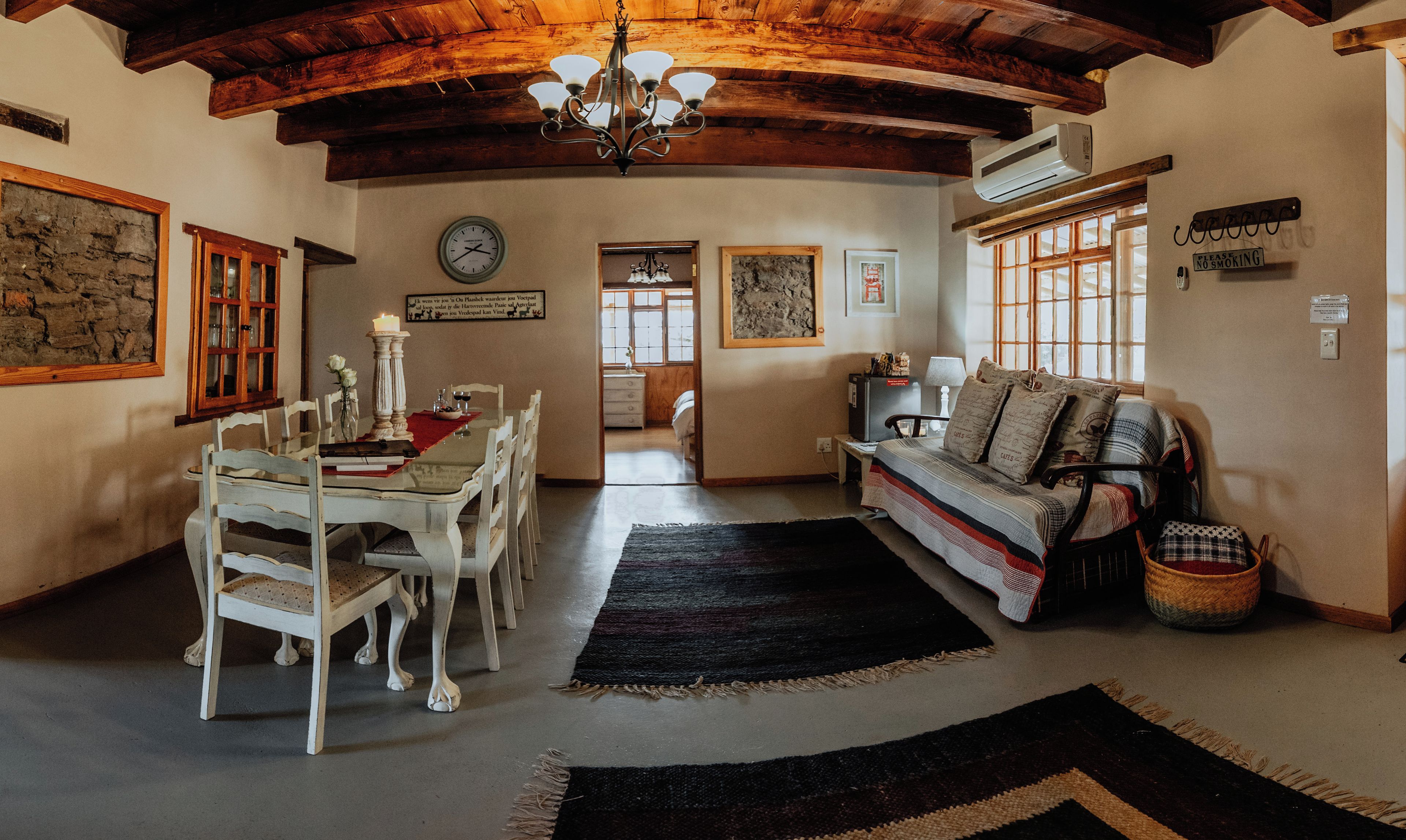 A dining area with a wooden table and chairs, a chandelier, and a clock on the wall.