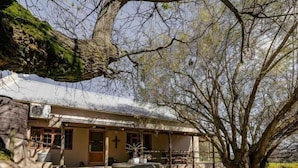 A building with a stone facade, a cross, and a courtyard with a stone bench and potted plants. - Dassenheuwel Farm Stay Homestead (Malmesbury)