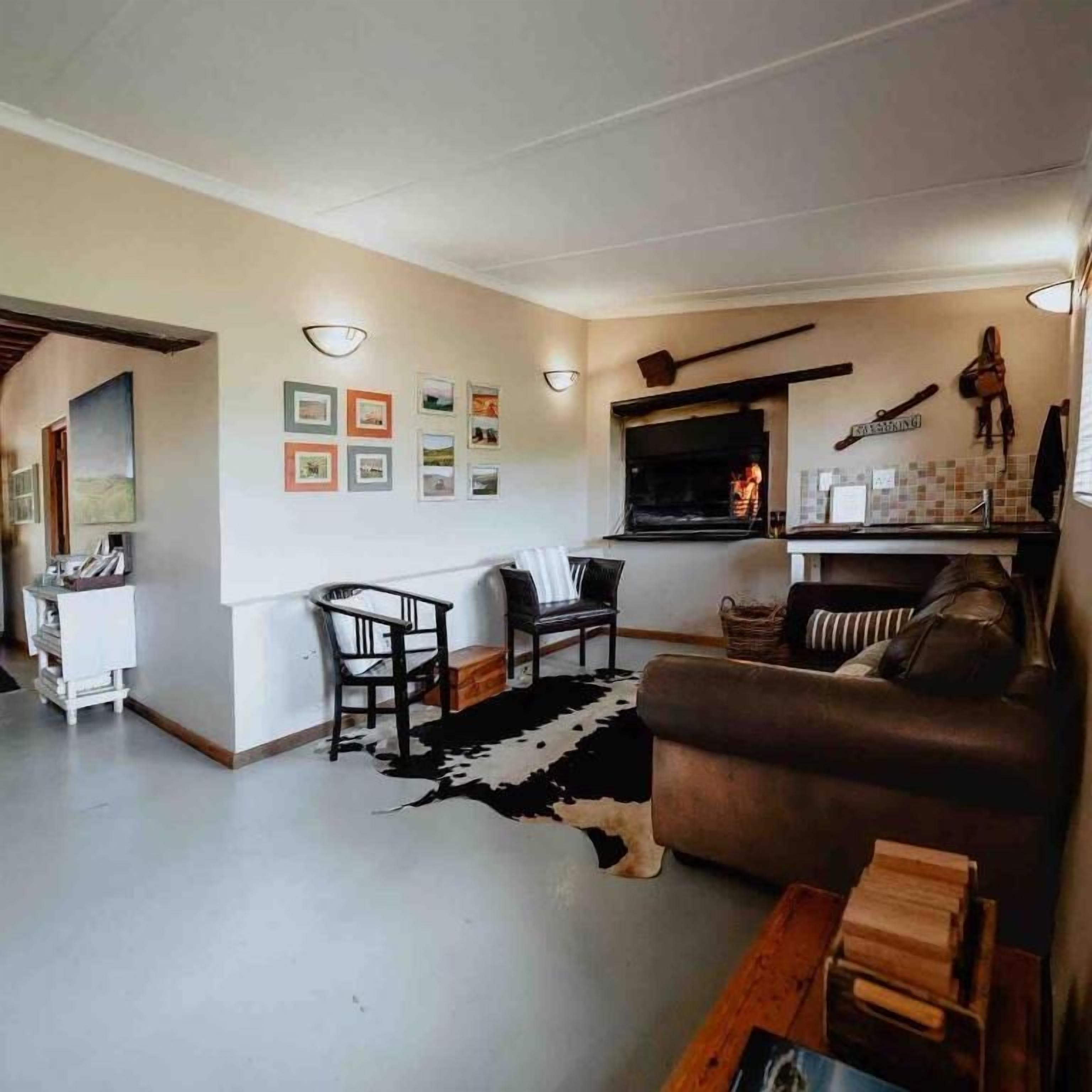 A living room with a fireplace, a sofa, a dining area, and a wall with framed pictures.